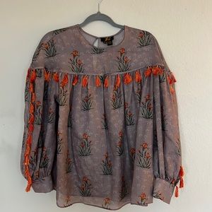 Purple flower patterned top with pom poms. See through. Like new. Size medium